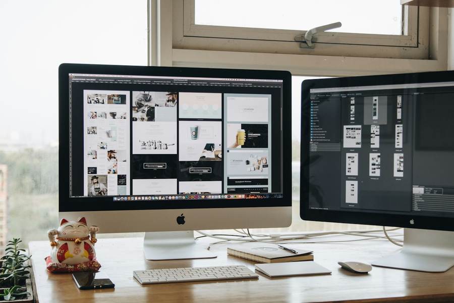 Deux écrans posés sur un bureau lumineux affichant un projet de site web