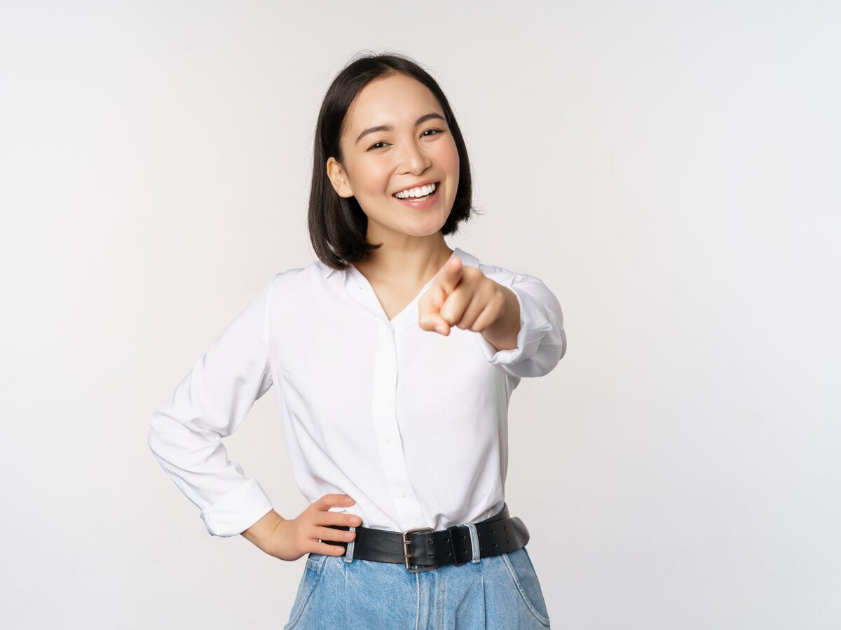 Femme souriante qui vous désigne du doigt